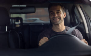 Taxi concept. Smiling minicab driver looking into rear view mirror